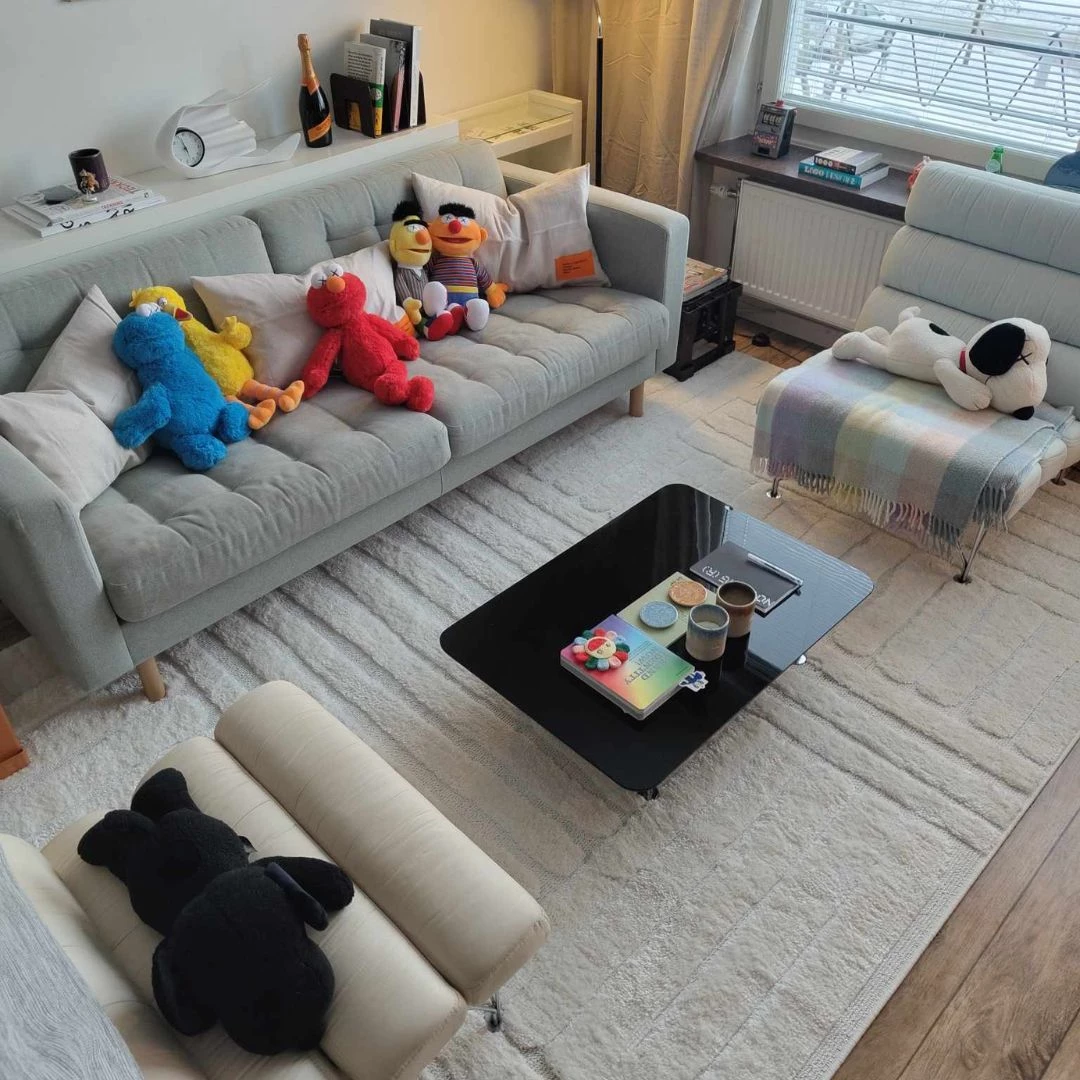 Moderne stue med lysegrå sofa, lænestol og sofabord på hvidt tæppe.